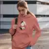 Femme portant un hoodie rose avec un design artistique féminin, idéal pour un look moderne et élégant.