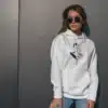 Femme portant un hoodie blanc avec un design artistique féminin, parfait pour une tenue décontractée et stylée.