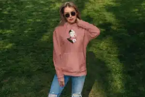 Femme portant un hoodie rose avec un design artistique féminin, idéal pour un look moderne et élégant.