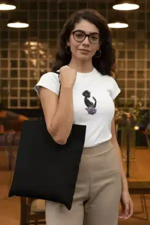 Femme portant un t-shirt blanc avec un dessin artistique de silhouette féminine et une rose violette, parfait pour un look élégant et moderne.