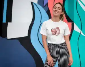 Femme portant un t-shirt blanc avec un design en forme de cœur artistique, idéal pour un look élégant.