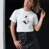 Femme portant un t-shirt blanc avec un dessin artistique représentant une femme élégante et des fleurs rouges, parfait pour un look chic et moderne.