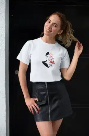 Femme portant un t-shirt blanc avec un dessin artistique représentant une femme élégante et des fleurs rouges, parfait pour un look chic et moderne.